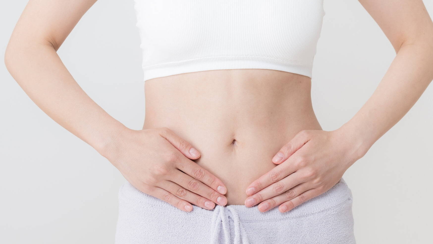 女性がお腹に両手を当てている様子